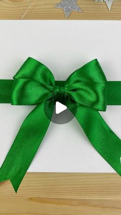 a green ribbon tied around a white card with silver stars on the top and bottom