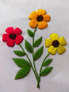 three different colored flowers on a white cloth