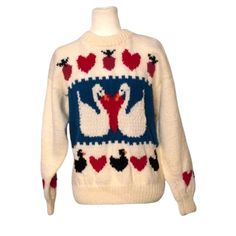 a white sweater with swans on it and hearts in the middle is hanging from a mannequin's head