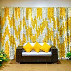 a couch sitting in front of a yellow and white wall with flowers on the side