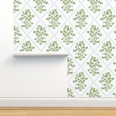 a white wall with green leaves on it and a roll of paper next to it