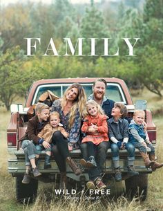 a family sitting in the back of a pick up truck with trees in the background