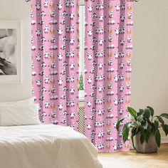 a bed room with a neatly made bed and pink curtains