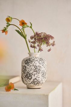 a white and black vase with flowers in it