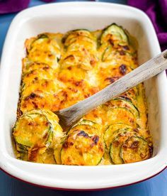 a casserole with zucchini and cheese in a white dish on a blue table