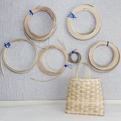 several pieces of woven material are arranged on the wall above a basket with blue handles