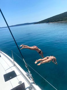 two people diving off the side of a boat