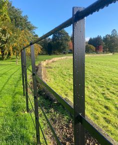 a metal fence in the middle of a grassy field