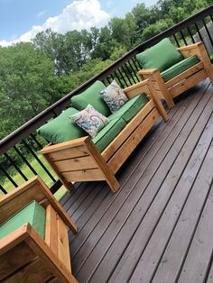 three wooden benches sitting on top of a wooden deck next to green cushioned cushions