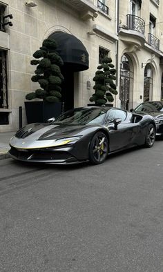 two black sports cars parked in front of a building