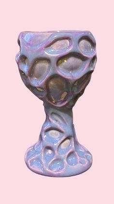 a purple vase sitting on top of a pink surface