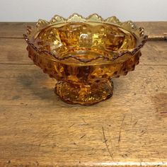 a glass bowl sitting on top of a wooden table next to a piece of wood