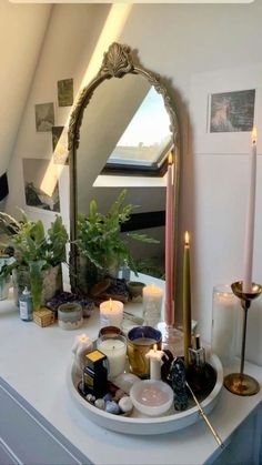 a mirror sitting on top of a white counter next to candles and other items in front of it