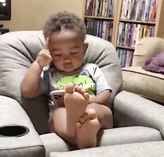 a little boy sitting on top of a gray chair