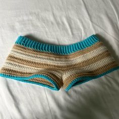 a crocheted shorts laying on top of a white bed next to a pillow