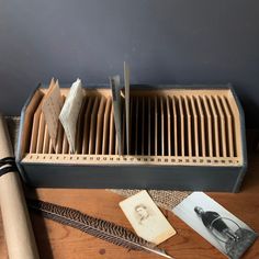 an old book is sitting on a table next to some feathers and other things that are laying around it