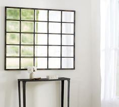 a console table with a mirror and vase on it in front of a white wall