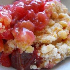 a close up of food on a plate with crumbs and fruit in it