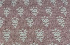 a close up view of a fabric with small white leaves on pink and beige background