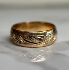 a gold wedding ring sitting on top of a white table