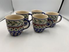 four coffee mugs sitting next to each other on a white counter top in front of a mirror