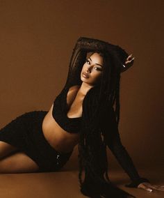 a woman with long black hair is laying on the floor wearing a skirt and top