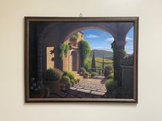 a painting hanging on the wall in front of a doorway with potted planters