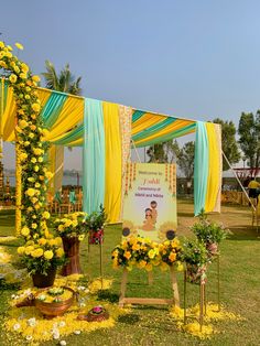 an outdoor ceremony with flowers and decorations on the grass, in front of a yellow drape