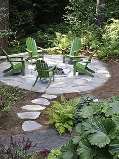 a fire pit surrounded by lawn chairs in the middle of a garden with green plants