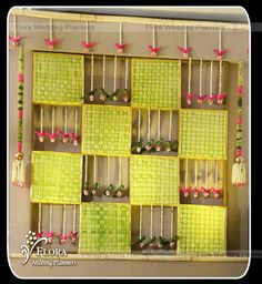 a wall hanging display with green tiles and pink flowers on the bottom, along with other items