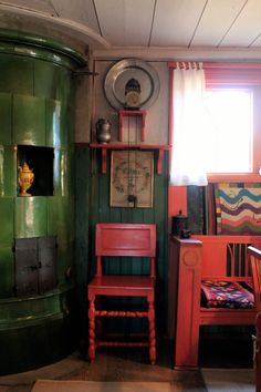 a room with green and red walls, wooden furniture and a clock on the wall