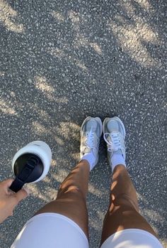 a person standing on the ground with their feet in a cup and shoes off to the side