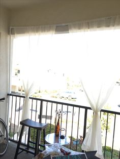 a balcony with two chairs and a table next to a bike parked on the sidewalk