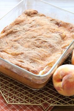 peach cobbler with two peaches on the side and a baking dish in front