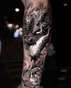 a man's arm with a dragon and rose tattoo design on the left forearm