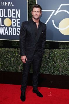 a man in a tuxedo standing on a red carpet at an awards event