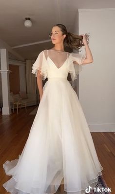 a woman in a white dress standing on a wooden floor with her hair blowing in the wind