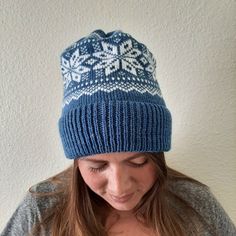 a woman wearing a blue and white knitted hat looking down at her cell phone