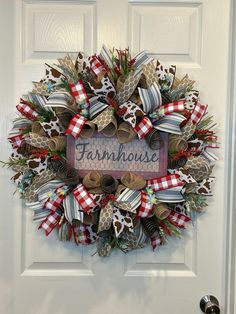 a wreath with the word farmhouse on it hanging on a door handle that is decorated with ribbons and pine cones