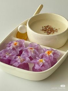 purple flowers in a white bowl and spoon