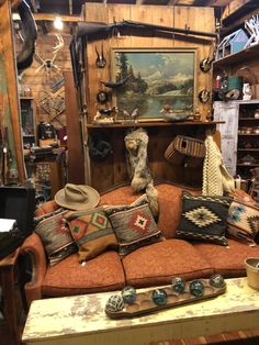 an old couch with many pillows and hats on it in a room filled with antiques