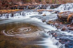 a small waterfall in the middle of a forest with lots of water flowing down it