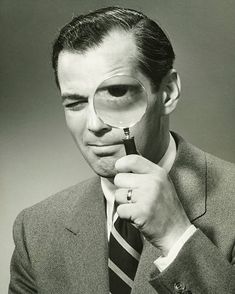 a man holding a magnifying glass to his face with one hand and looking through it