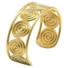 a gold cuff bracelet with spiral designs on the front and back of it, against a white background