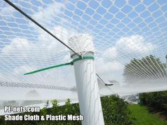 a close up view of the top of a soccer goal net with grass and bushes in the background