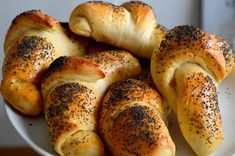 a white plate topped with bread rolls covered in poppy seeds