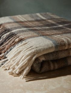 two blankets folded on top of each other in front of a light colored wall and floor