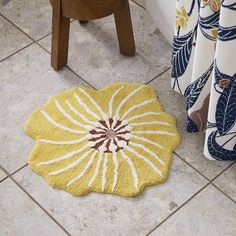 a yellow and white rug sitting on top of a floor next to a shower curtain