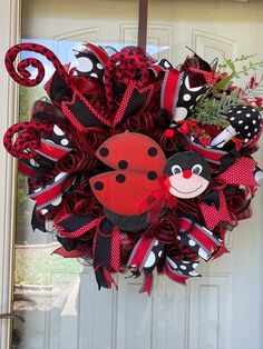 a red and black wreath with a ladybug on it hanging from the front door