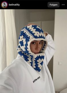 a person wearing a blue and white crochet hat with a scarf around their head